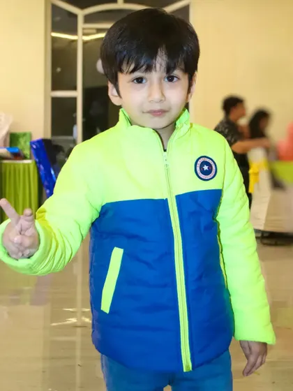 A young boy in a colorful jacket gives a peace sign to the camera. We capture the fun and playful personalities of the kids at your event.
