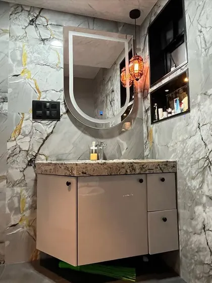 A detailed shot of the vanity area, highlighting the marble-patterned countertop and the simple, elegant design of the floating cabinet and mirror.