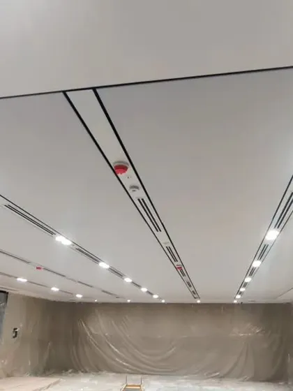 A view of a soundproof ceiling during installation. The fabric-finished panels are designed to absorb sound, and we've integrated linear lighting and air vents for a clean, seamless look.