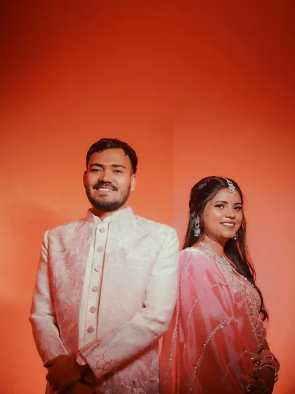 A modern couple portrait against a vibrant orange background. The simple composition and bold color make this a striking and memorable shot from their engagement.