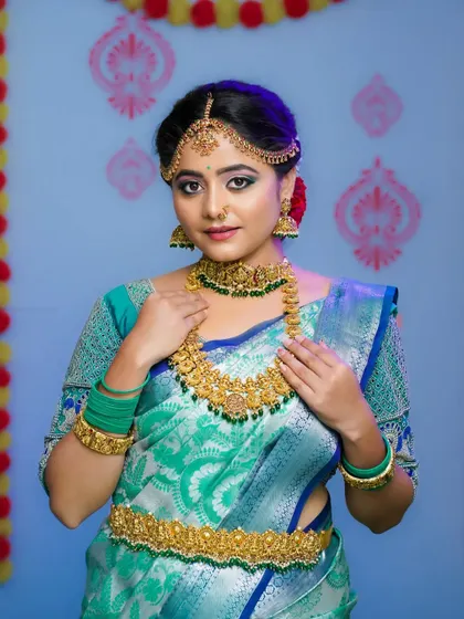 A vibrant bridal makeover portrait for a makeup artist's portfolio. The colorful background and expert lighting make the model's features and the traditional attire pop.