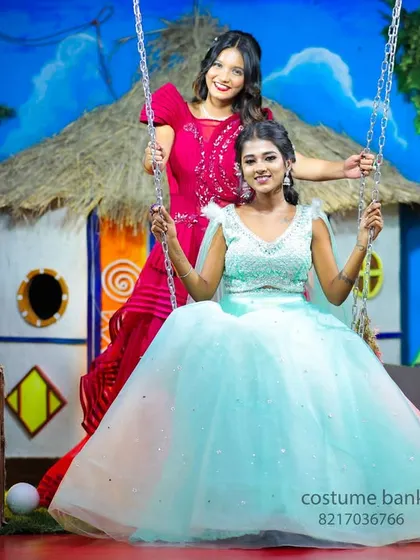 Two models posing on a swing in my village-themed studio set, one in a modern gown and the other in a traditional dress, showing the variety of shoots I offer.
