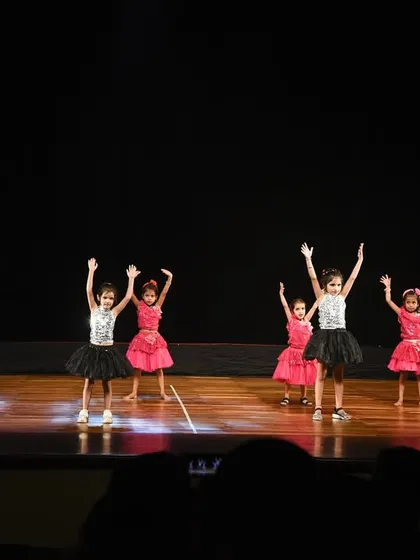 The group with arms raised high, celebrating the joy of dance in front of a packed audience.