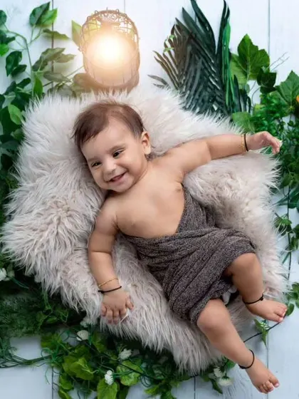 A relaxed 5-month-old baby in a cozy nest surrounded by greenery. This setup is great for younger babies who are not yet sitting up on their own.