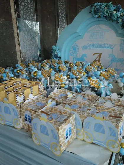 A beautifully arranged table of party favors, all coordinated with the blue and gold prince theme. The custom-designed boxes and gift bags ensure that guests take a piece of the magic home with them.
