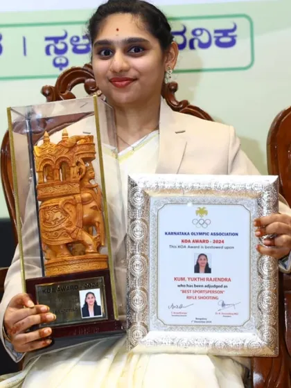 A close-up of our shooter, Ms. Yukthi Rajendra, proudly displaying her Karnataka Olympic Association (KOA) Award and certificate for being named 'Best Sportsperson'.