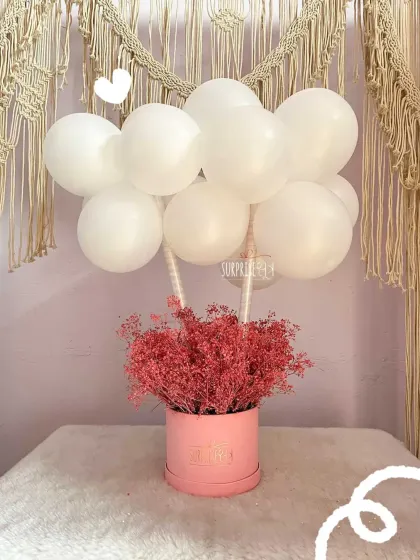 A simple yet elegant bouquet featuring a cloud of white balloons floating above a box of delicate pink dried flowers. It's a chic and modern way to send your love.