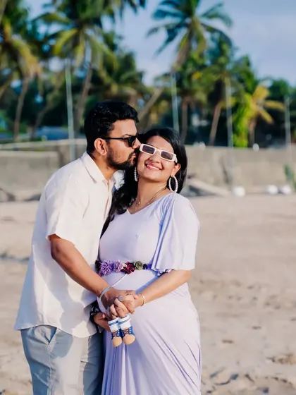 A playful and sweet moment during a beach maternity session. A gentle kiss on the cheek shows the love and affection between the couple as they celebrate this special time.