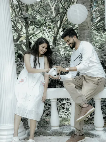 A cute moment where the groom shows the bride a picture on a polaroid camera, set in a beautiful garden gazebo.