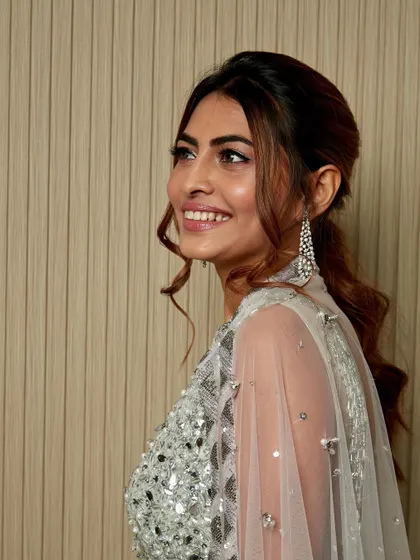 A candid smile from this beauty, showing off her sparkling cocktail look. The face-framing tendrils add a soft, romantic touch to the glamorous ponytail.