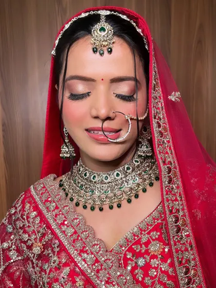 The complete look for my stunning bride in her red lehenga. The makeup is balanced, with glowing skin, defined eyes, and a soft lip color that completes the traditional ensemble.