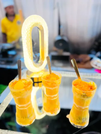 Glasses of Mango Falooda elegantly displayed on a mirrored surface with mood lighting.