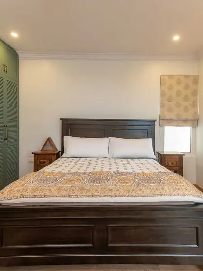 This bedroom features a statement wardrobe with dusty green louvered doors, adding a touch of vintage charm and color to the otherwise minimalist space.