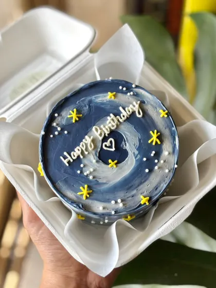 A starry night bento cake with a beautiful blue and white swirl, yellow stars, and a sweet birthday message.