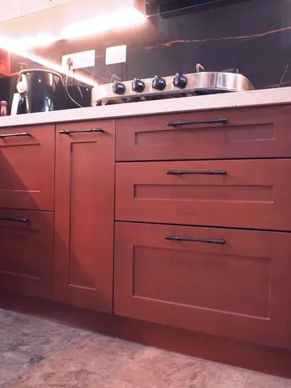A classic kitchen design featuring rich, dark red wood cabinets with a shaker-style profile. The black handles and white quartz countertop provide a beautiful contrast, creating a warm and inviting atmosphere.