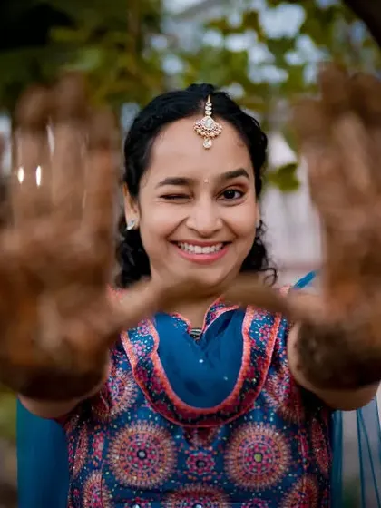A playful bride winks at the camera, showing off her intricate Mehendi design. This shot captures her fun personality and the beauty of the henna art.