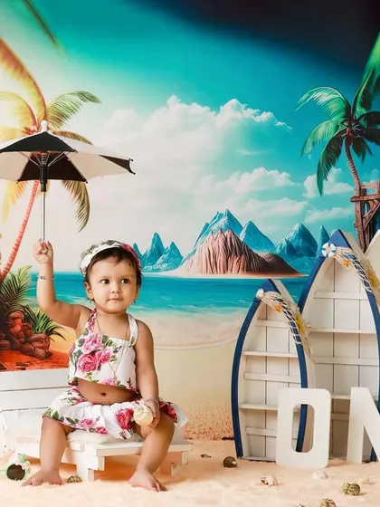 Holding her little umbrella, the birthday girl is ready for a sunny celebration. The colorful beach backdrop makes for a lively and cheerful first birthday portrait.