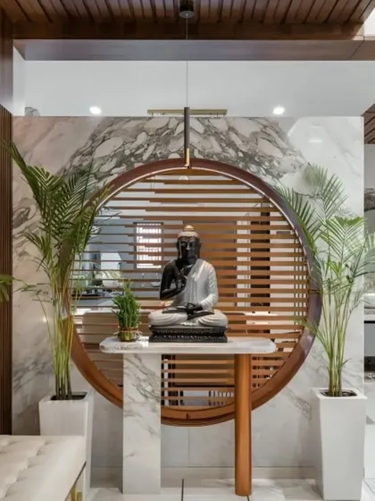 A serene and striking foyer centered around a Buddha statue. We designed the circular wooden frame and slatted backdrop, which is set against a white marble wall.