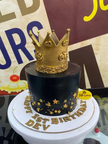 A chic 1.5kg first birthday cake in black and gold, topped with an ornate golden crown.