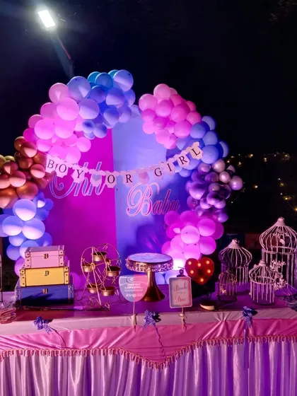 A "Boy or Girl" themed baby shower decoration. The backdrop is split between pink and blue, surrounded by a matching balloon arch, building anticipation for the big reveal.