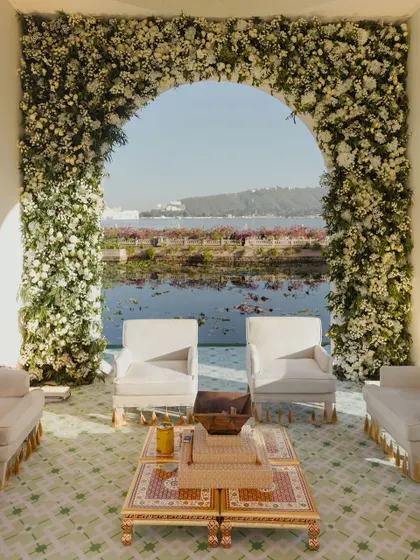 A serene, all-white floral archway framing a view of Lake Pichola in Udaipur. This mandap design was about minimalist elegance, letting the stunning natural backdrop speak for itself.