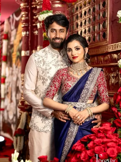 A classic couple portrait from their reception. The bride's royal blue saree and red blouse are complemented by a timeless makeup look.