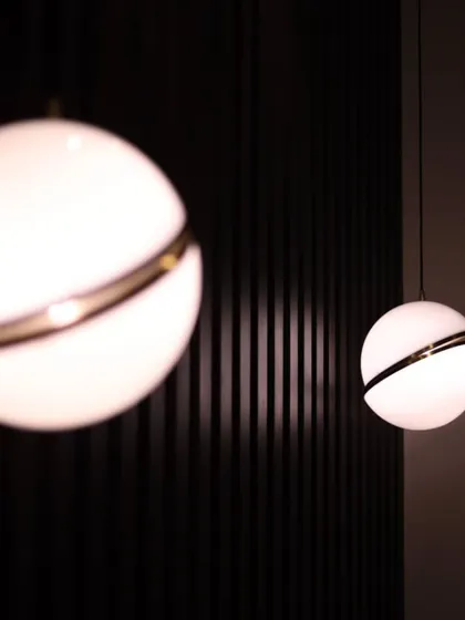 A close-up of modern globe pendant lights with a brass accent ring. We use lighting not just for illumination but as a key decorative element that defines the character of a space.