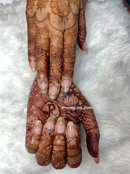 A complete view of the bridal hands, showcasing the beautiful interplay between the mehndi and the custom nail art. The glitter ombré extensions add length and elegance, completing her look.