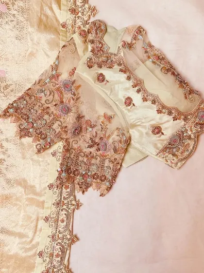 A pastel blouse and saree set with intricate, delicate embroidery.