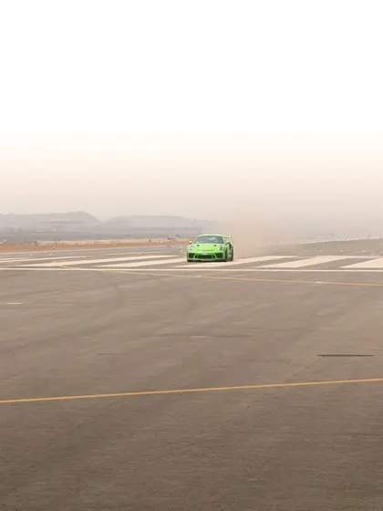 Using negative space to create a sense of scale, this image shows the green Porsche as a small but powerful subject on a vast, empty runway.