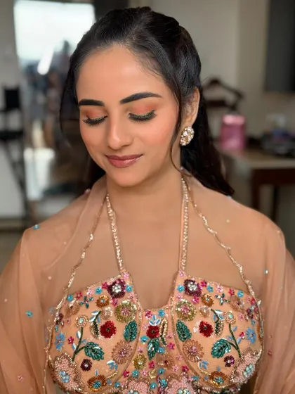 A close-up of the bride's eye makeup, showing the soft peach tones on the lid and the bold green winged liner.