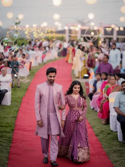 The grand entrance. The couple walks down the red carpet at their outdoor engagement ceremony, surrounded by guests, looking like true royalty.