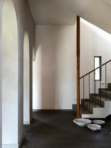 The main staircase at Maison Rouge, with its clean lines, simple railing, and arched hallway. The design is a study in minimalism, allowing the natural textures of the walls and floors to stand out.