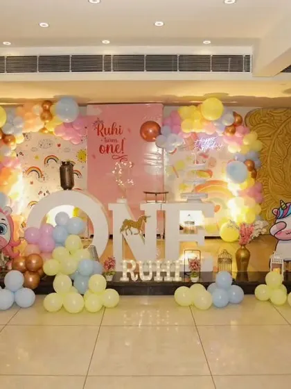 A unicorn and rainbow themed first birthday, with large "ONE" letters and cute character props.