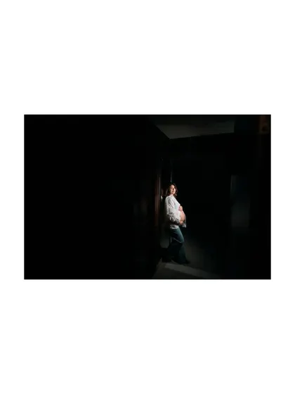 Another perspective of the dramatic, low-key lighting setup. This image captures the quiet strength and beauty of pregnancy in a minimalist and artistic way.