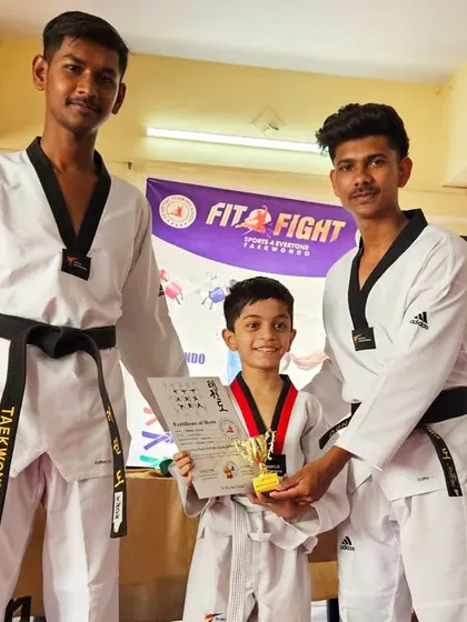 A young fighter receives his trophy and certificate from our coaches. Belt exams are an exciting time for students to showcase their progress.