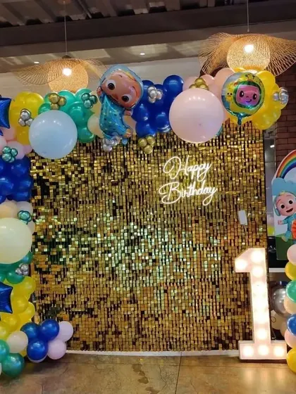 A Cocomelon theme with a twist. The gold sequin wall adds a touch of sparkle behind the colorful characters and balloons, making the setup extra special.