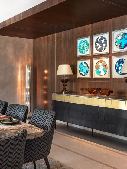 A view of the dining area's custom sideboard with a marble top and brass-finished base. The curated art and lighting complete this sophisticated space for entertaining.