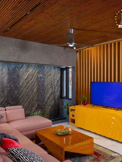 A bold and contemporary living room with a unique color palette. The pink sectional sofa, bright yellow TV console, and textured stone wall create a vibrant and artistic space.