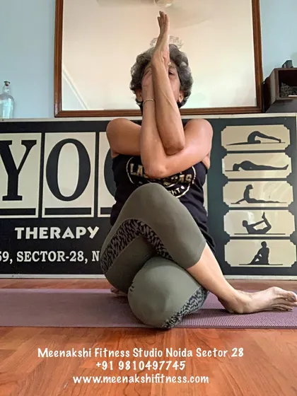 Garudasana, or Eagle Pose, shown here in a seated variation. This pose is excellent for stretching the shoulders and upper back while also opening the hip joints.