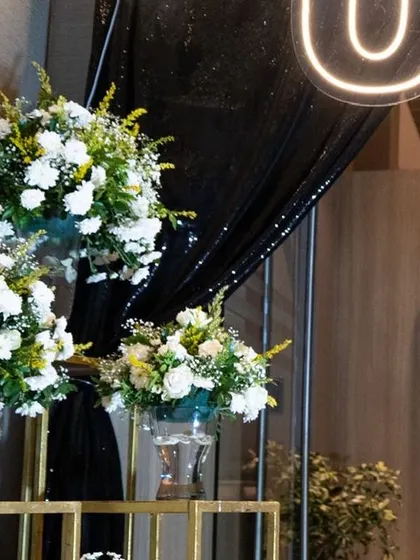 The entrance to the 50th birthday party set the stage for an unforgettable night. The contrast between the dark, sparkling drapes and the fresh white flowers created a sophisticated and grand first impression.