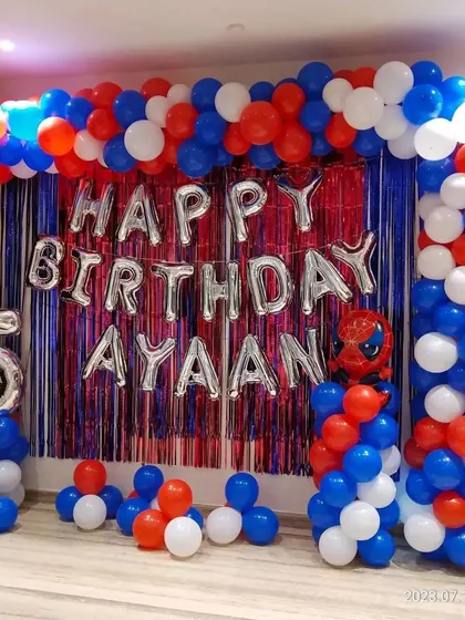 A classic Spider-Man theme for a 5th birthday. This decoration features a red and blue tinsel curtain, a large balloon arch, and 'Happy Birthday' foil letters.