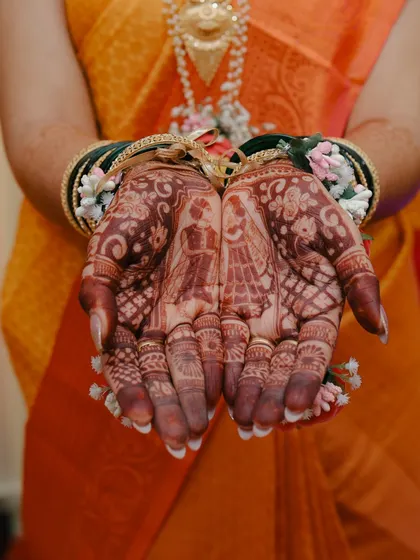 A close-up shot of the bride's hands, showcasing her beautiful henna and floral bracelets.
