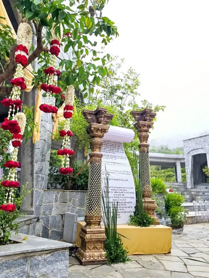 A side view of the vow scroll installation, showing the hanging red floral garlands and the beautiful stone venue.