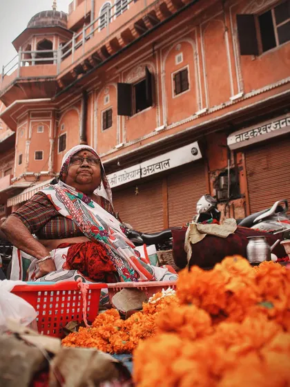A flower seller in a Jaipur market, surrounded by bright orange marigolds. The colors and her proud expression capture the creative and daring spirit of the local people.