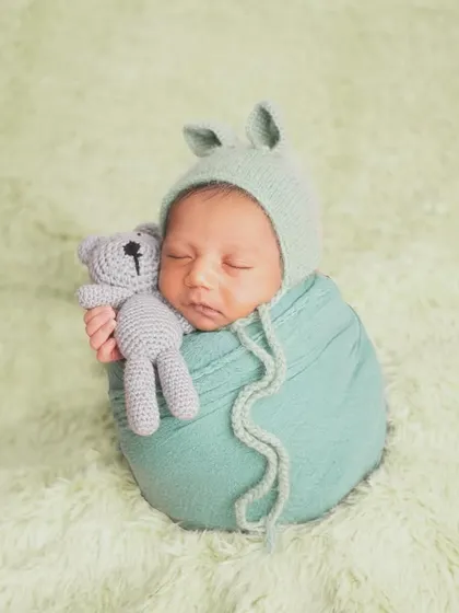 This little bunny is just the cutest! I have a collection of adorable bonnets, headbands, and props to add a touch of personality to your newborn's photoshoot. Here, he's snuggling a tiny teddy bear.