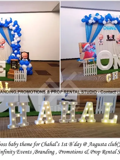 This simple and elegant Boss Baby theme for a first birthday at Augusta Club features a curtain backdrop with a blue and white balloon arch. A large "ONE" table and marquee letters add a touch of sophistication to the fun theme.