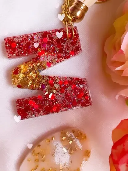 A close-up of the sparkling red and gold glitter inside this 'M' initial keychain. I love adding tiny heart glitters for an extra touch of love.