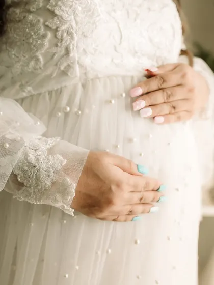 It's all in the details. This close-up on the hands resting on the baby bump, showing off the beautiful pearl details of the gown, tells a story of love and anticipation.