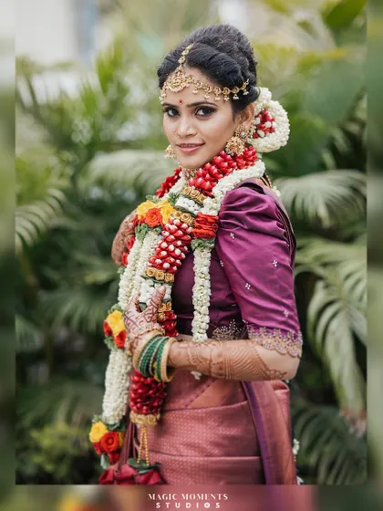 A beautiful portrait of the bride, Snigdha, in her traditional wedding saree and floral garlands, looking radiant.